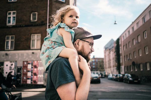 一名男子带着他的小女儿在城市里散步。