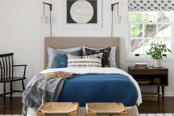 一间带有许多存储解决方案的卧室，包括床头柜，篮子和两个行李架（已放在床脚）