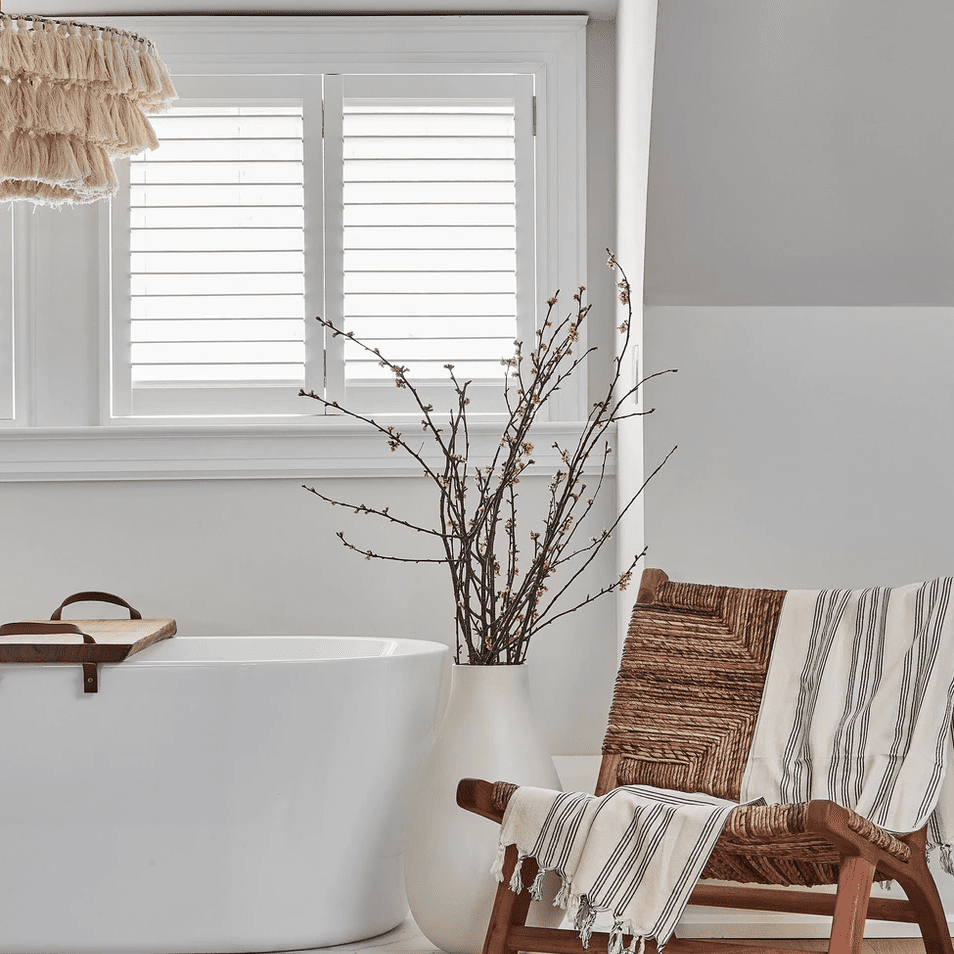 白色的浴室里有一把编织的躺椅