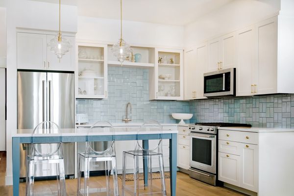 装修厨房与蓝色瓷砖后挡板和干净的酒吧凳。