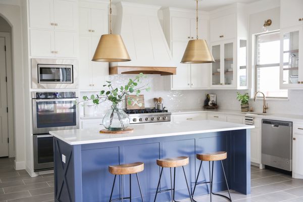 有蓝色海岛和金垂饰光的白色厨房。