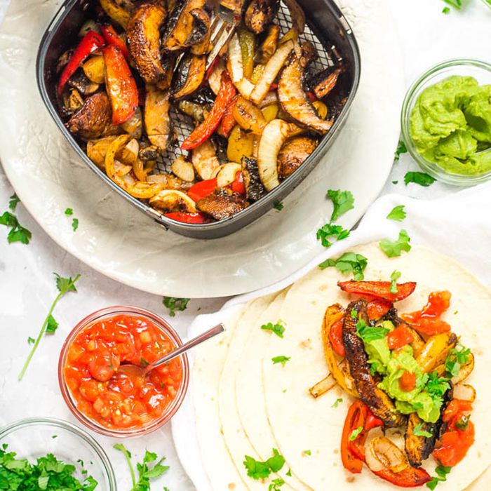 Fajita浇头在一堆玉米饼旁边的空气炸锅里供应