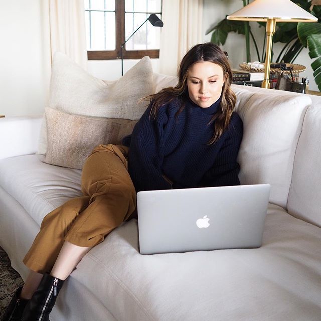 一个女人坐在沙发上为她的笔记本电脑做预算。
