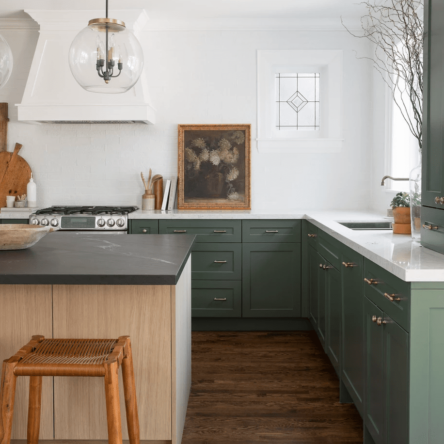 厨房里有绿色的橱柜和深色的硬木地板