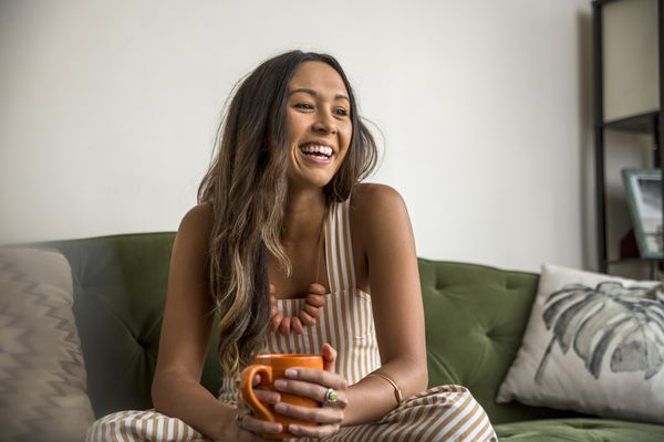 手拿咖啡杯大笑的时尚女人”class=