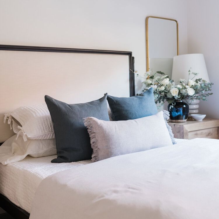 中性床与亚麻枕头和木制床头柜。