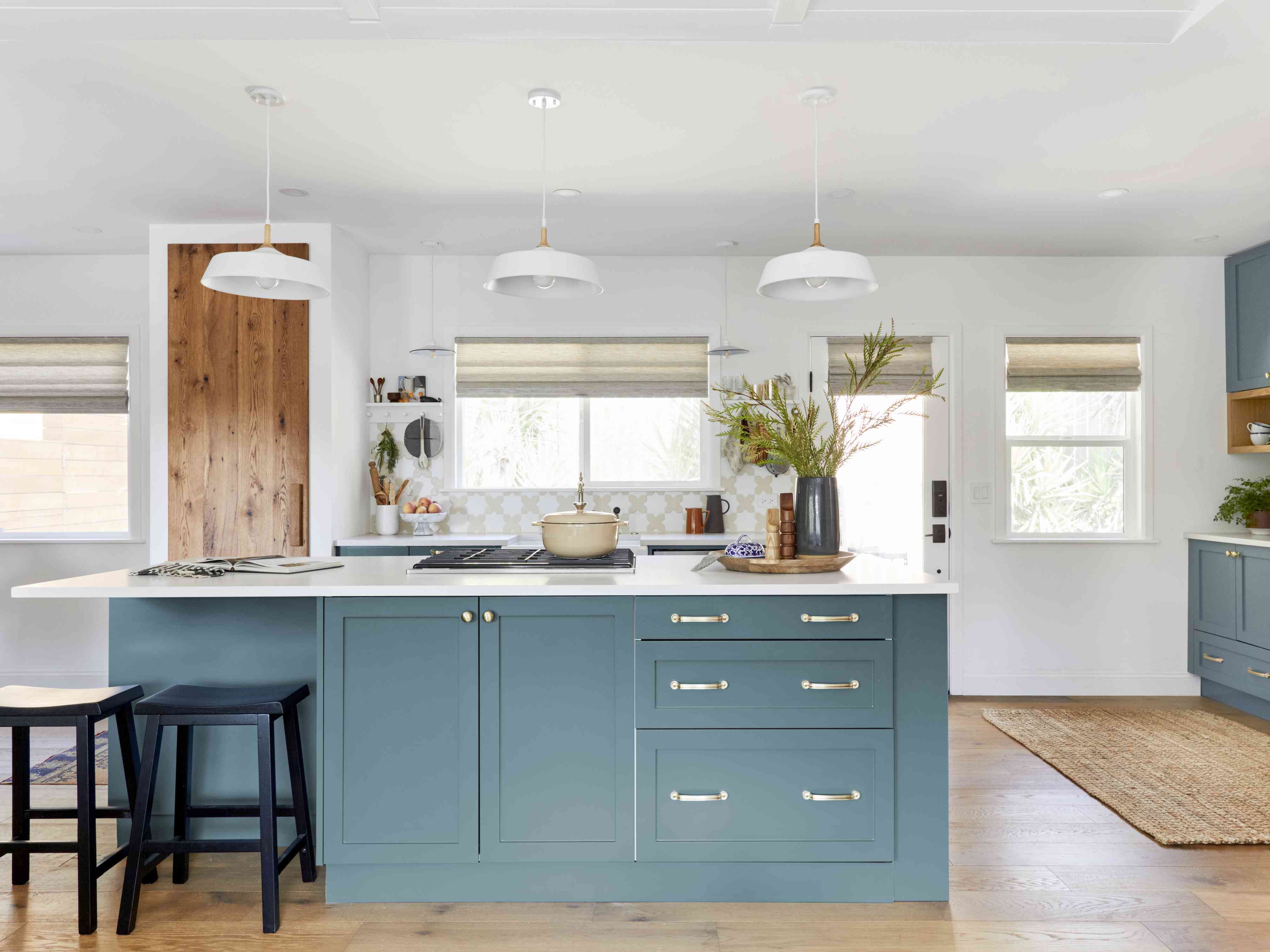 蓝绿色厨房岛白色厨房与白色吊灯。