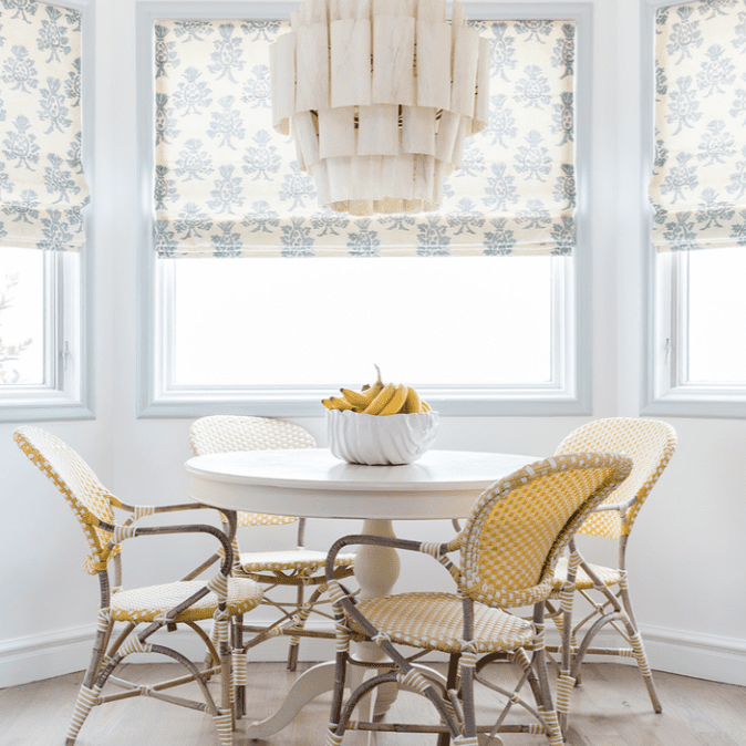 一张圆形的厨房桌子，周围是黄色的椅子，上面放着一碗香蕉