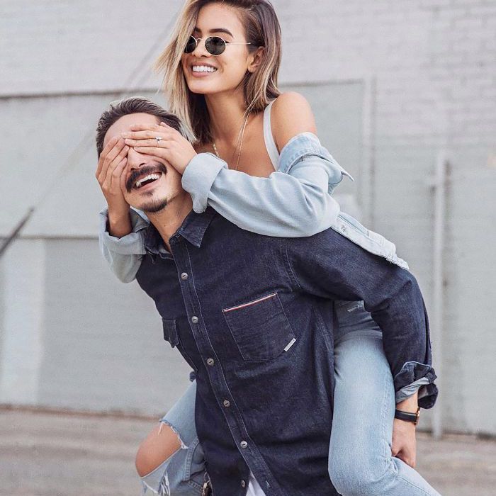 一个爱玩的男人，背着一个女人，女人的手盖在他的眼睛上。
