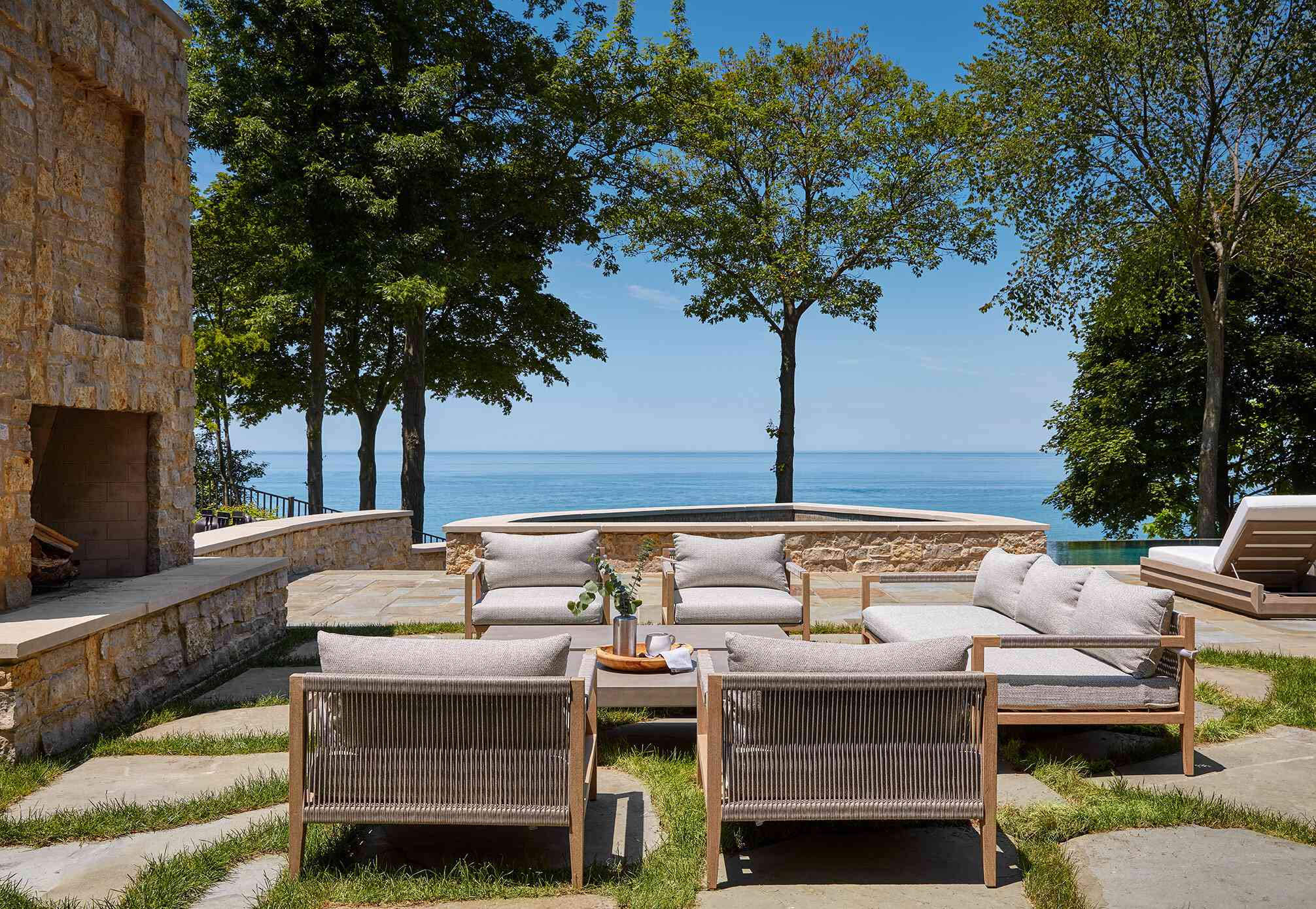 室外壁炉周围有几张舒适的室外扶手椅和一个豪华的室外沙发