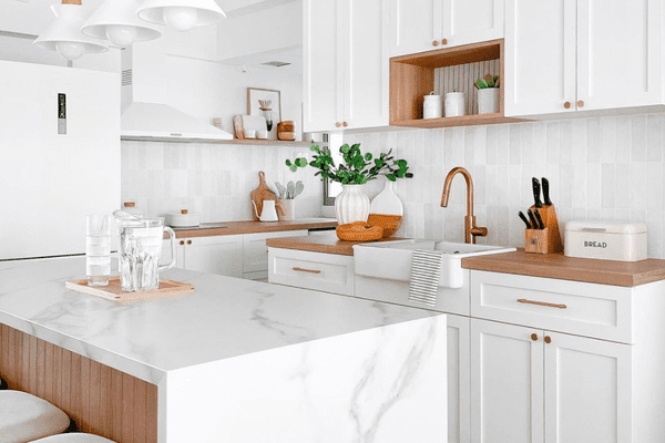 一个小型厨房，白色橱柜，白色台面和白色吊灯