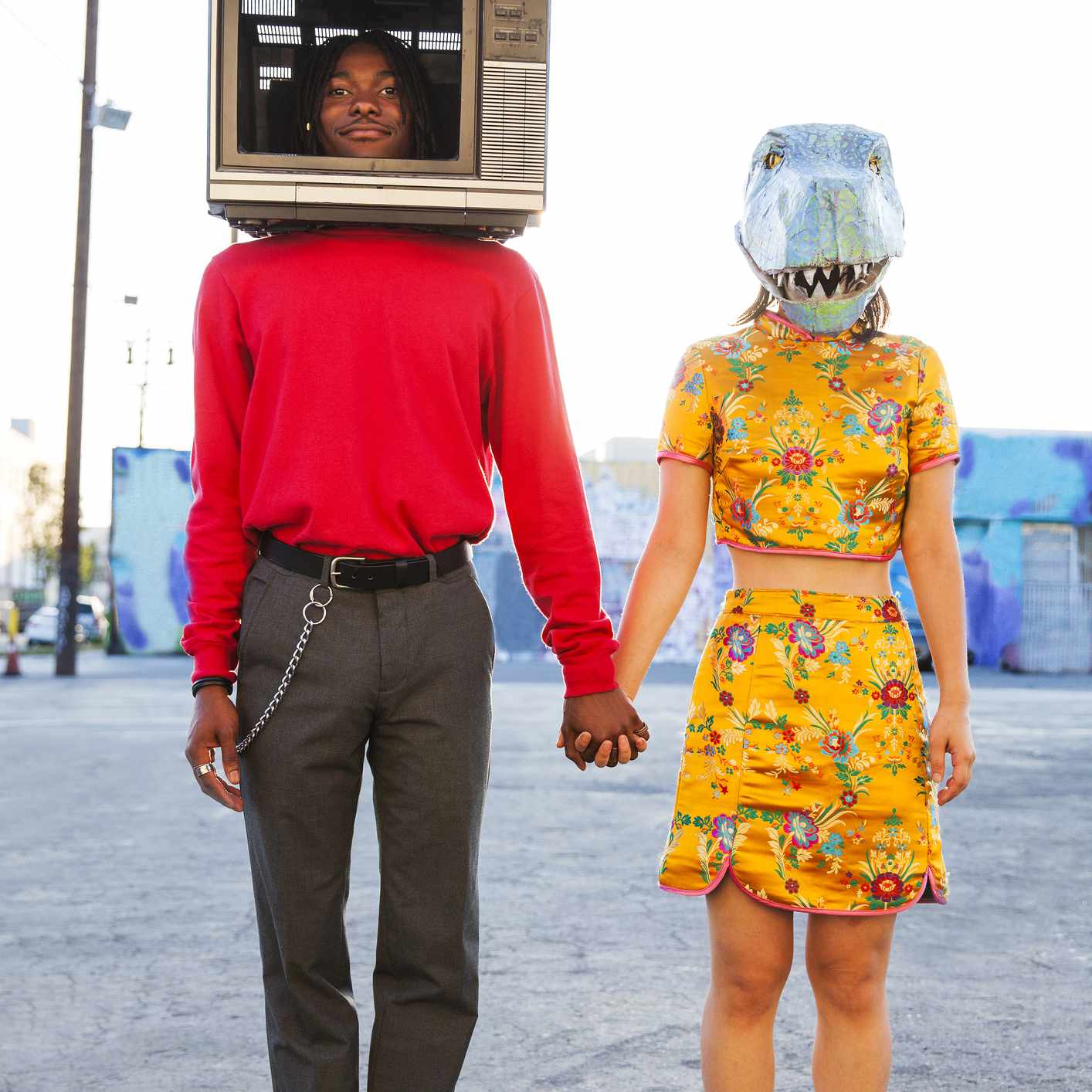 年轻人在他的头上和女人穿着恐龙面具的电视。