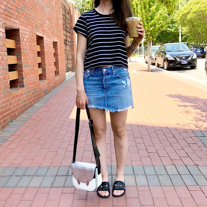 一个长发女人穿着条纹t恤，牛仔裙和黑色的游泳池滑梯。