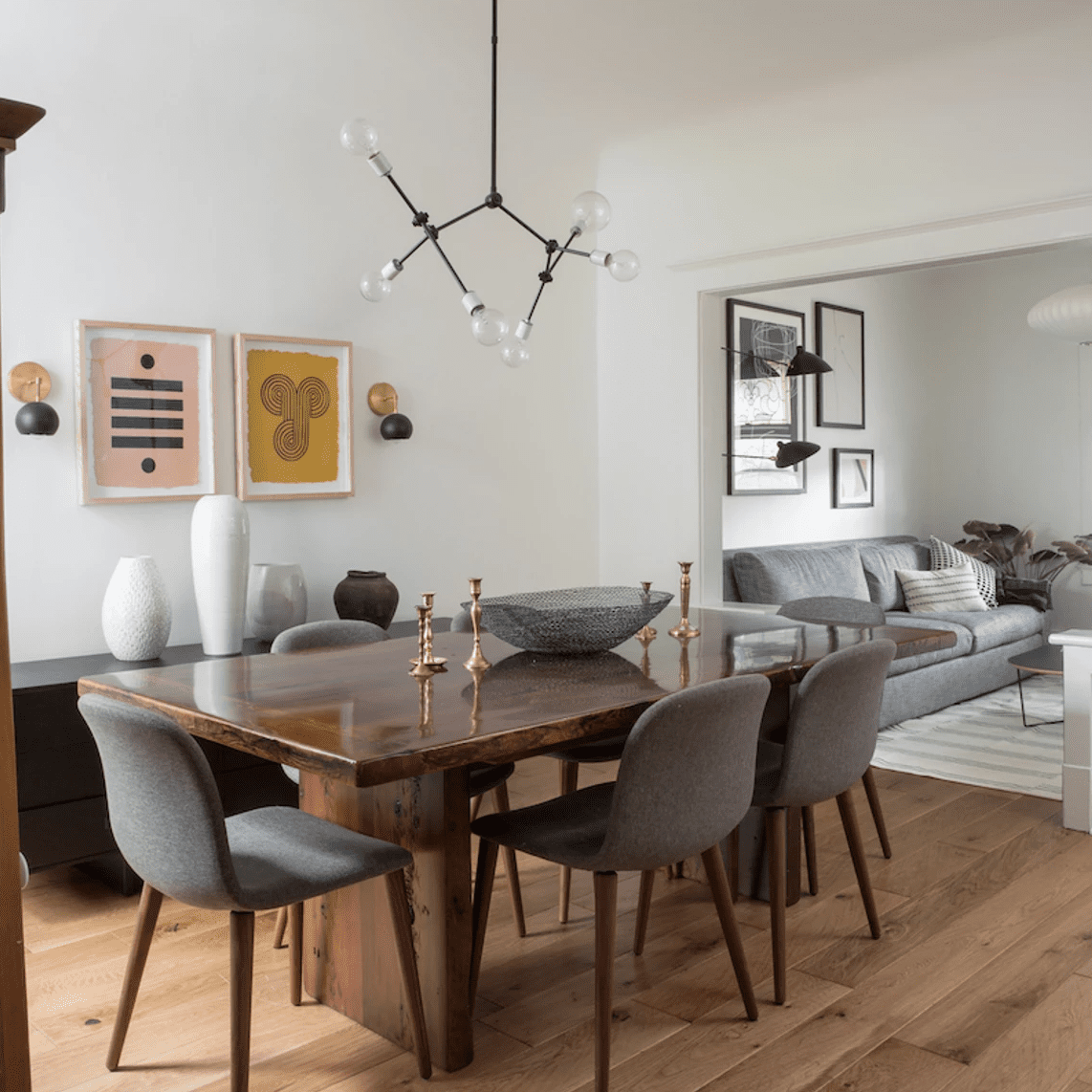 一个光滑的餐桌，上面有一个大金属碗和几个空的金烛台