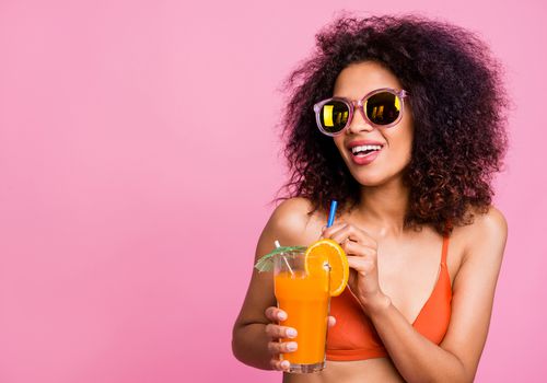 女人拿着一杯鸡尾酒，橙色的轮子和提基伞。