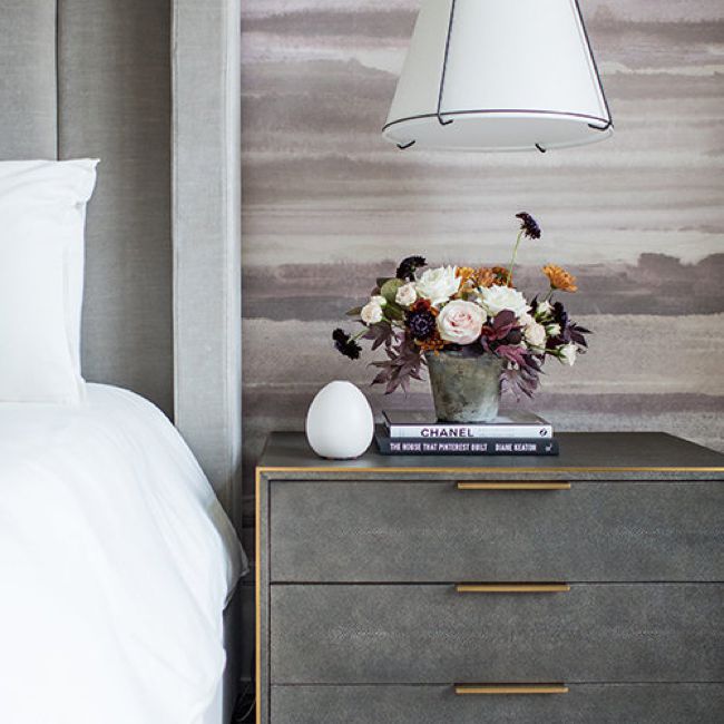 卧室配有灰色的床和床头柜和紫色水彩壁纸