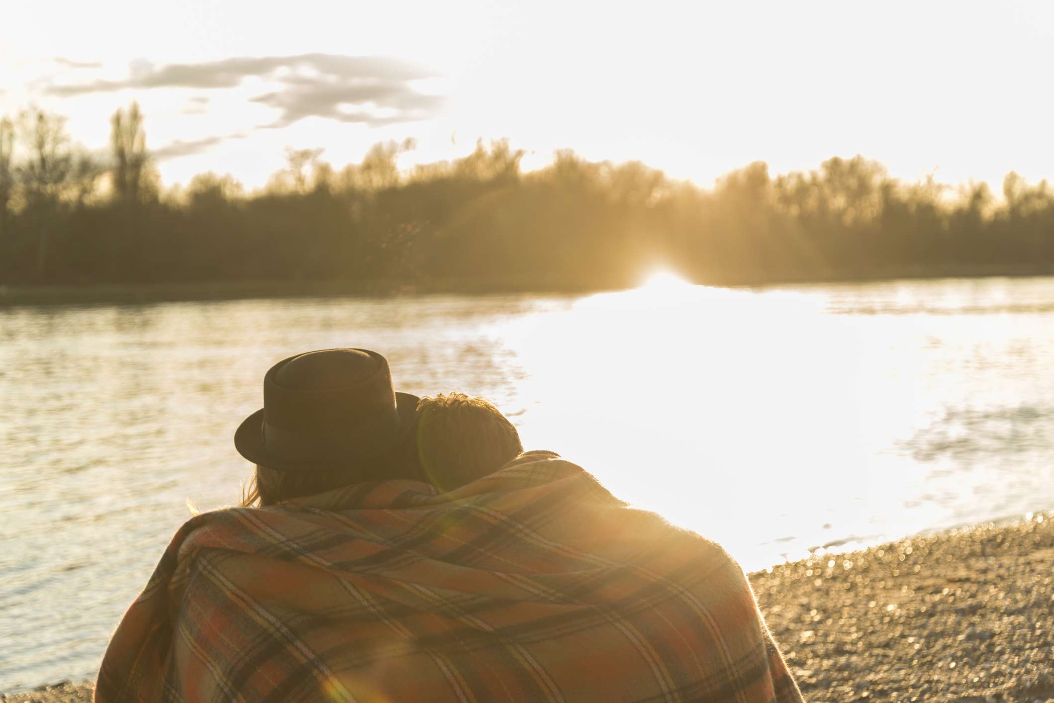 夫妇裹在毯子，坐在湖边看着太阳