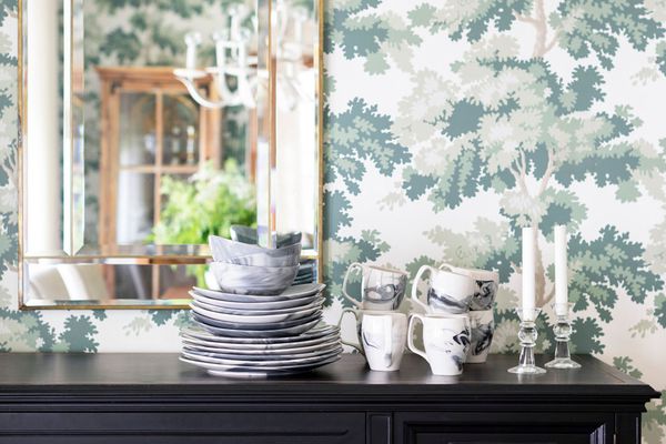 古色古香的侧桌用瓷中国和在它后的印刷的墙纸。