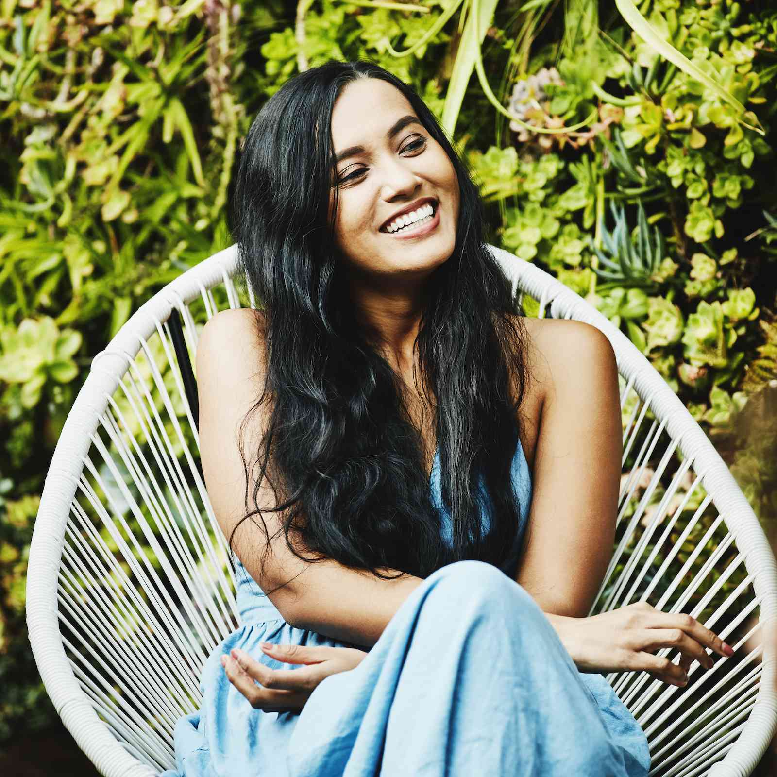 一个女人坐在一把绳椅上，面带微笑，看上去很开心。