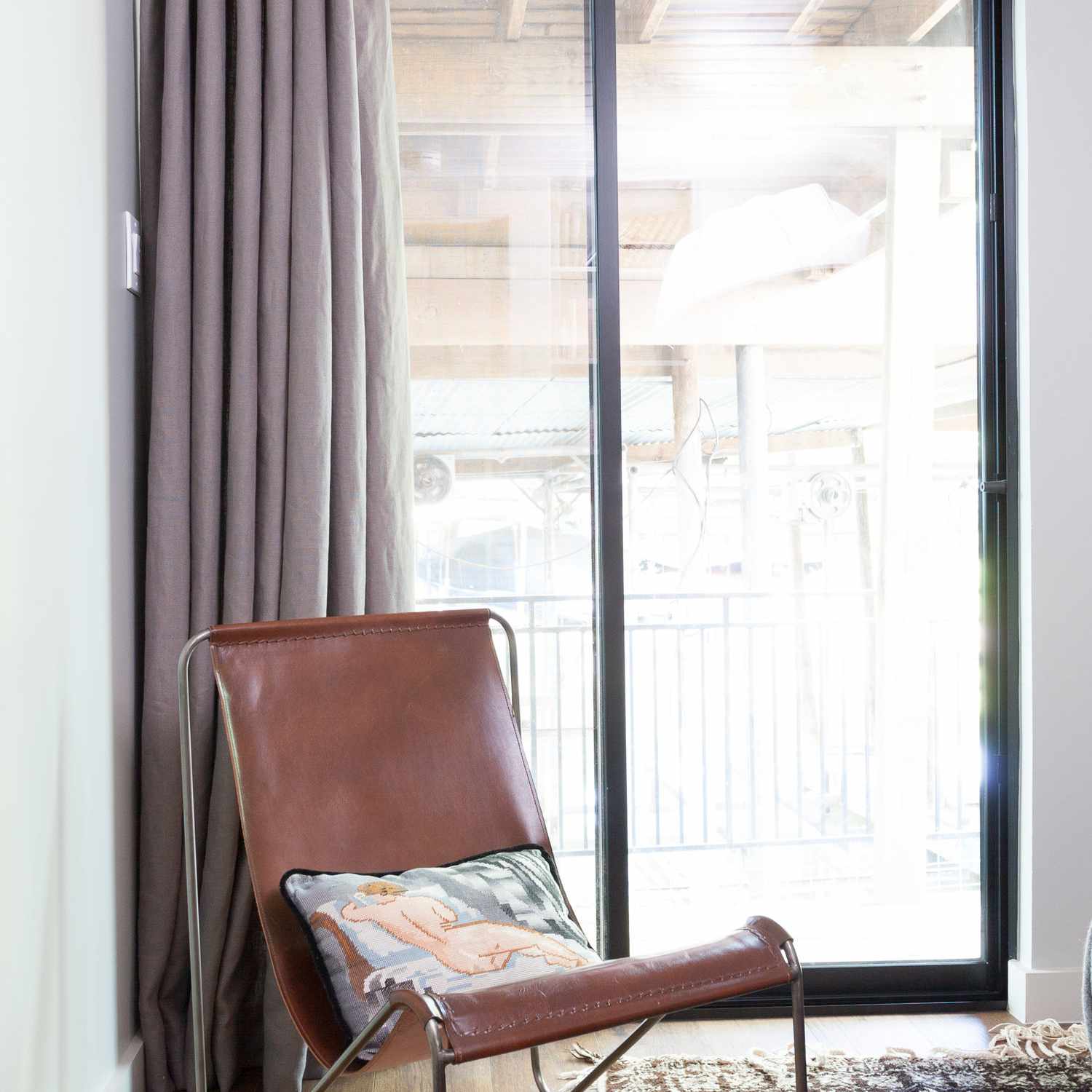 卧室的角落里挂着淡紫色的窗帘和一把棕色的皮椅子
