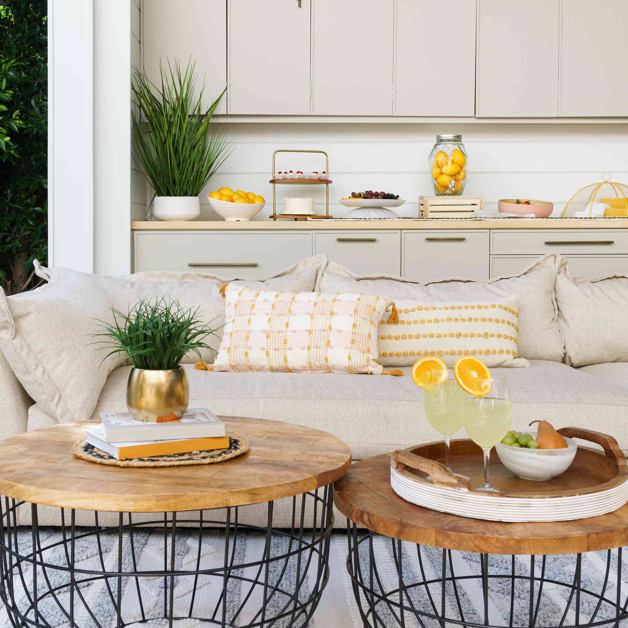 户外空间米色沙发和两张木制咖啡桌。