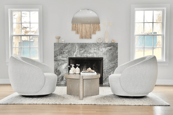 一间带灰色大理石壁炉和两个圆形椅子的大胆起居室