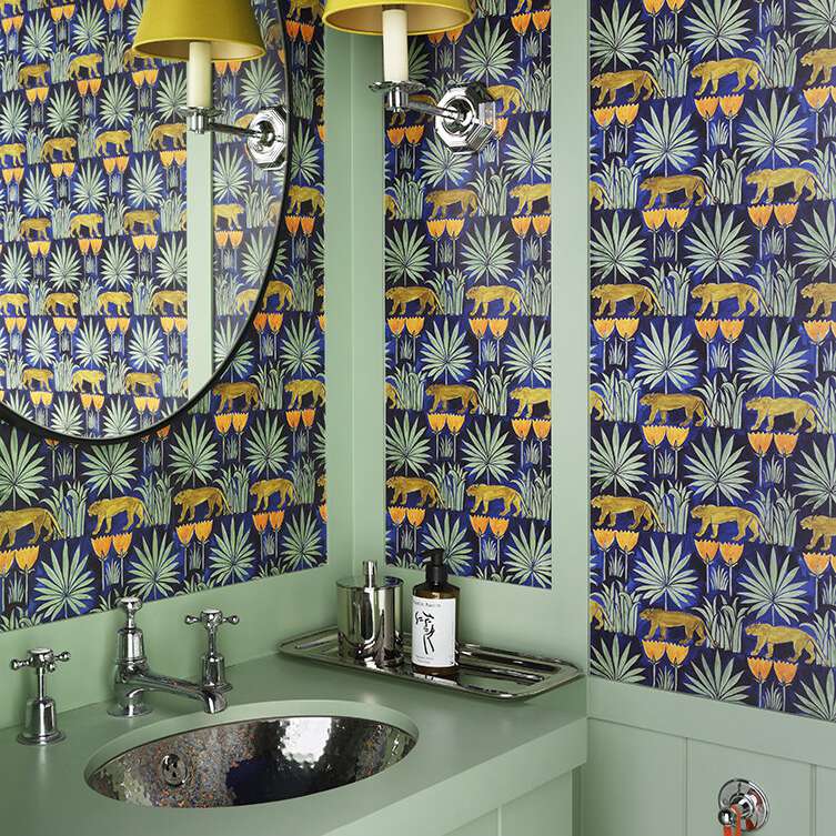 浴室里有橙色和蓝色的壁纸和绿色的水槽