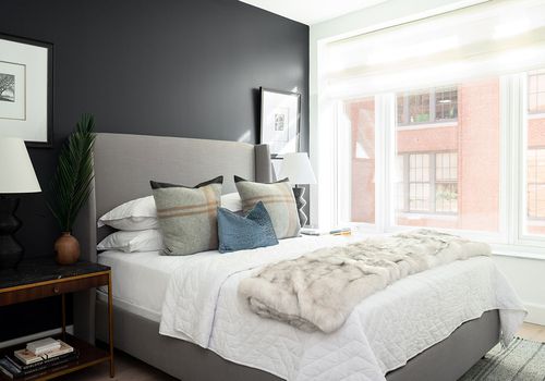 bedroom with black accent wall and gray bed