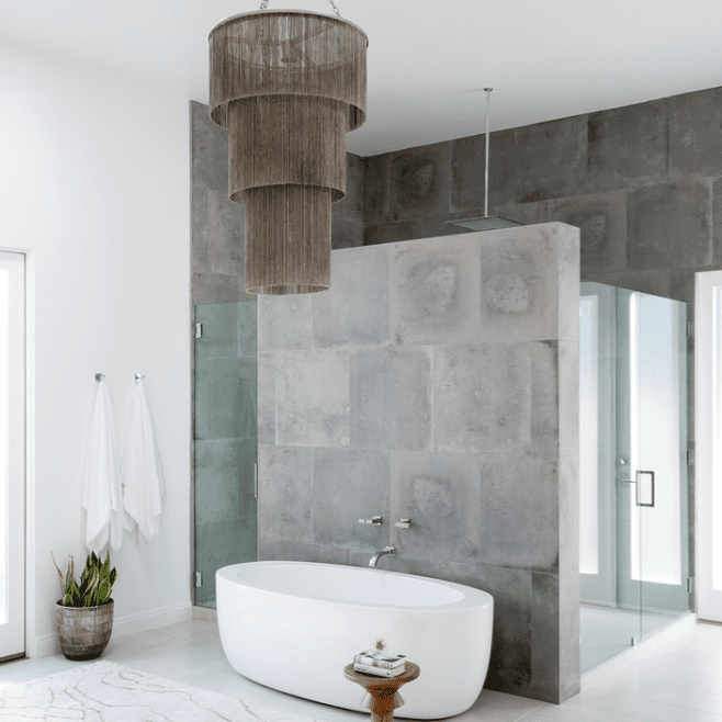 一间混凝土浴室，里面有一盏大胆的分层吊灯
