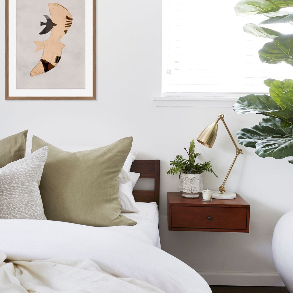 一间极简主义风格的卧室，配有一盏光滑的金色台灯