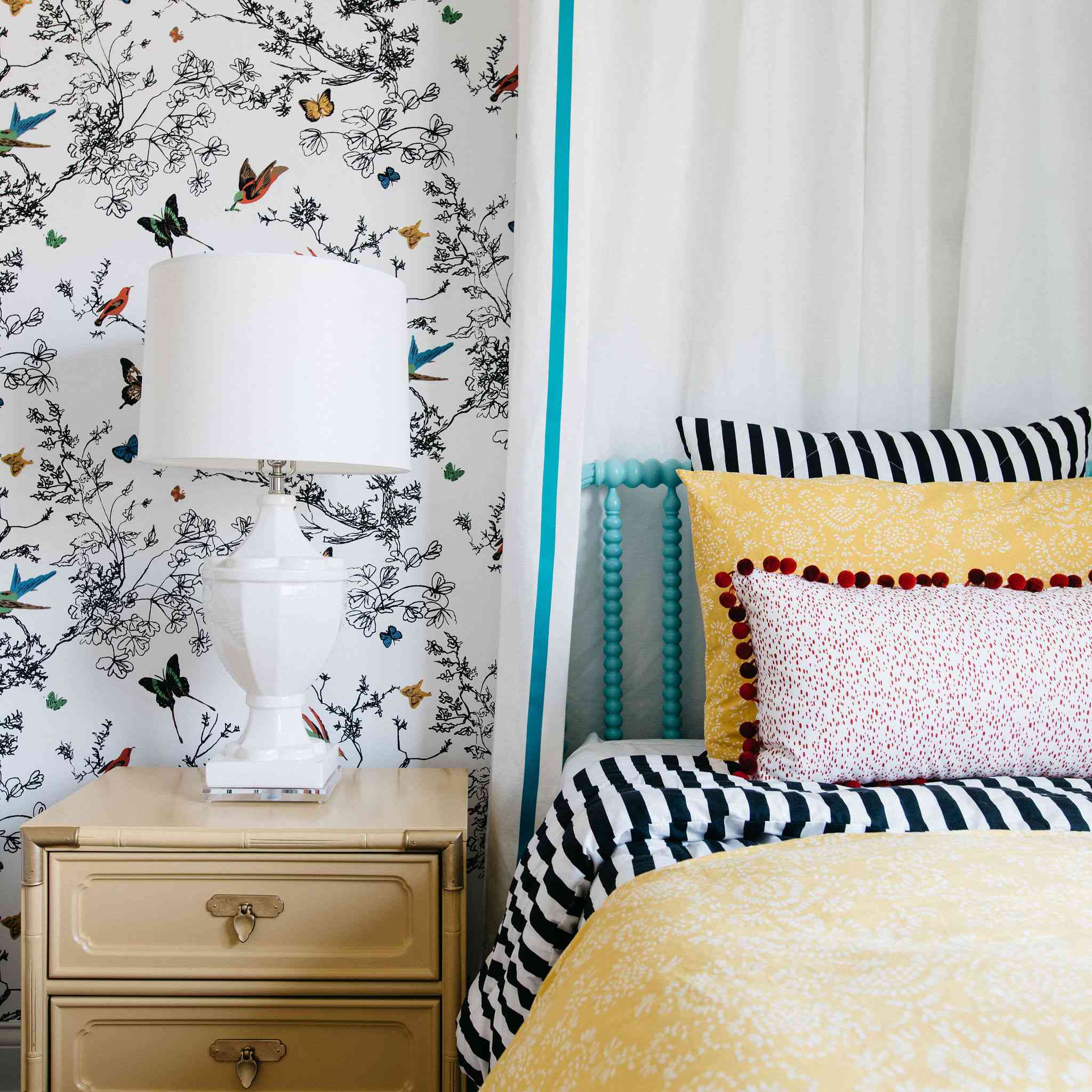 在阳光明媚的黄色的床上用品和花纹壁纸的卧室。