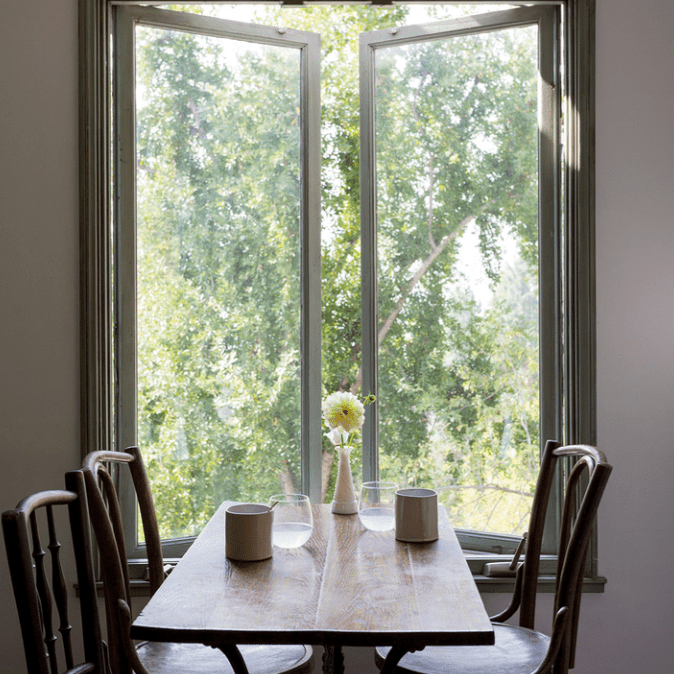 一张小餐桌，上面装饰着一个细长的白色花瓶，花瓶里插着一朵雏菊