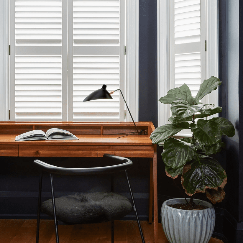 一间有着靛蓝色墙壁、白色窗户和一张木桌的家庭办公室