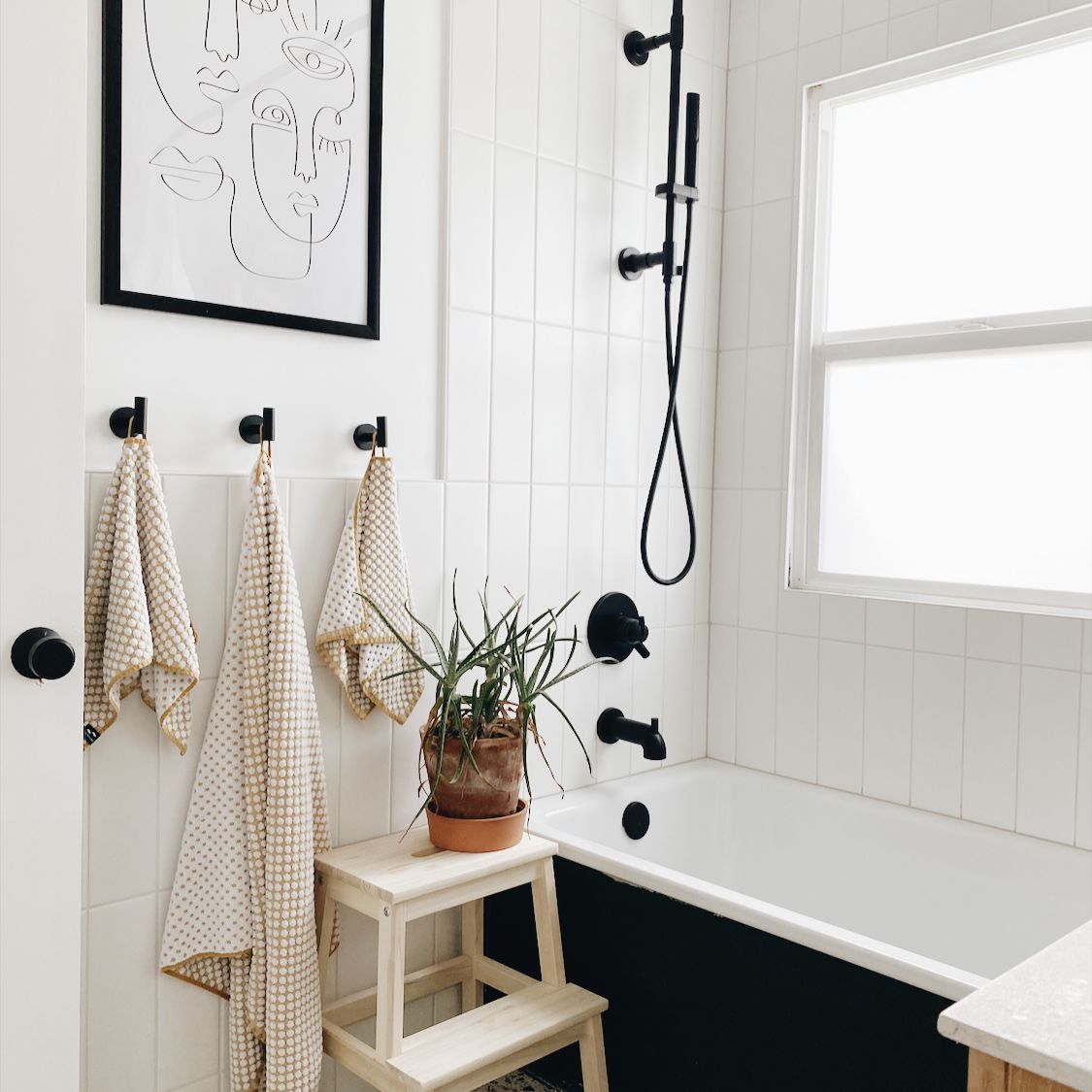 浴室配有水磨石地板，黑色夹具和植物