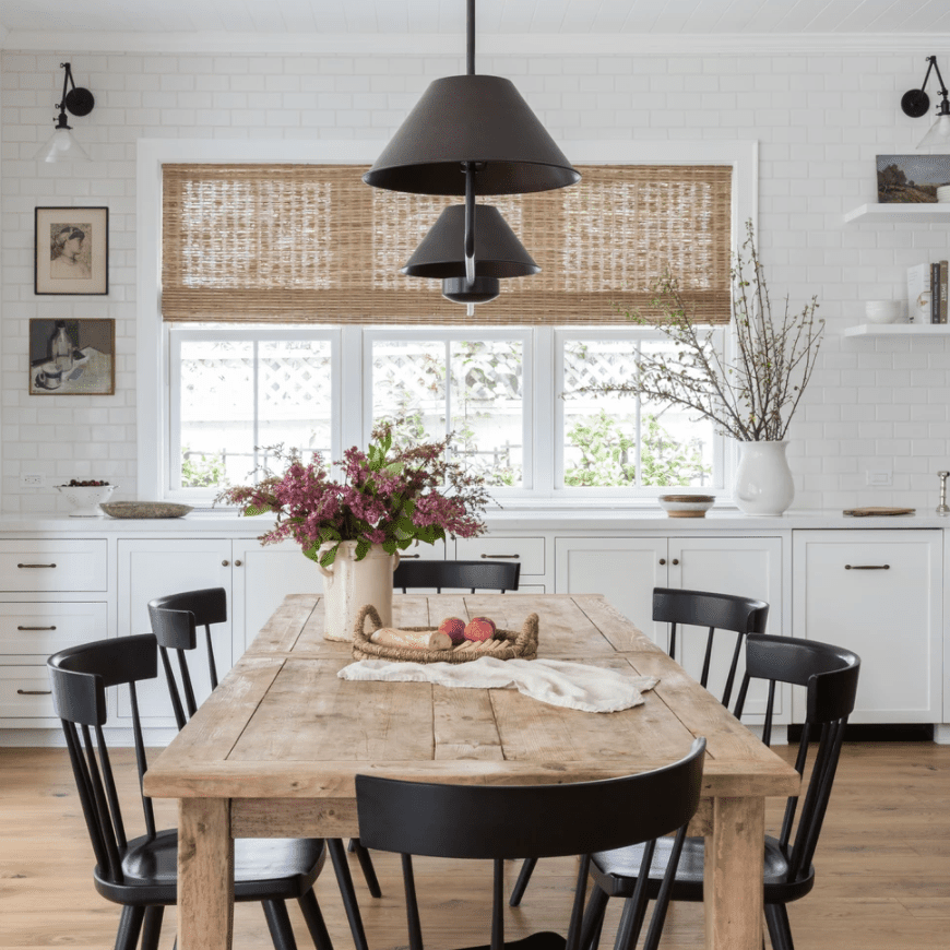 一张质朴的餐桌，上面有一个装满鲜花的花瓶和一个上面有面包和水果的托盘