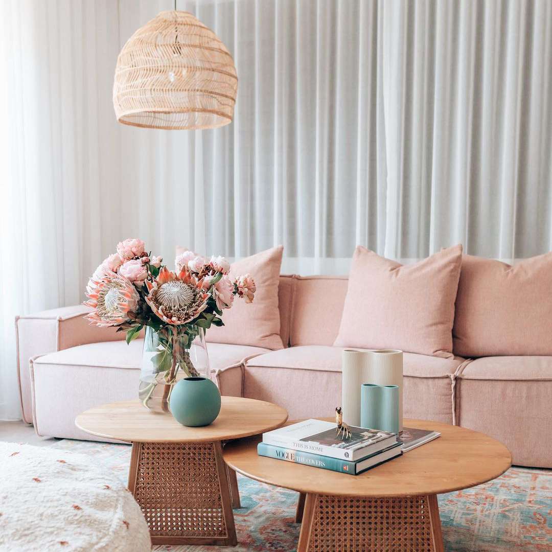 桃红色沙发旁边的咖啡桌与仿造花卉花束。