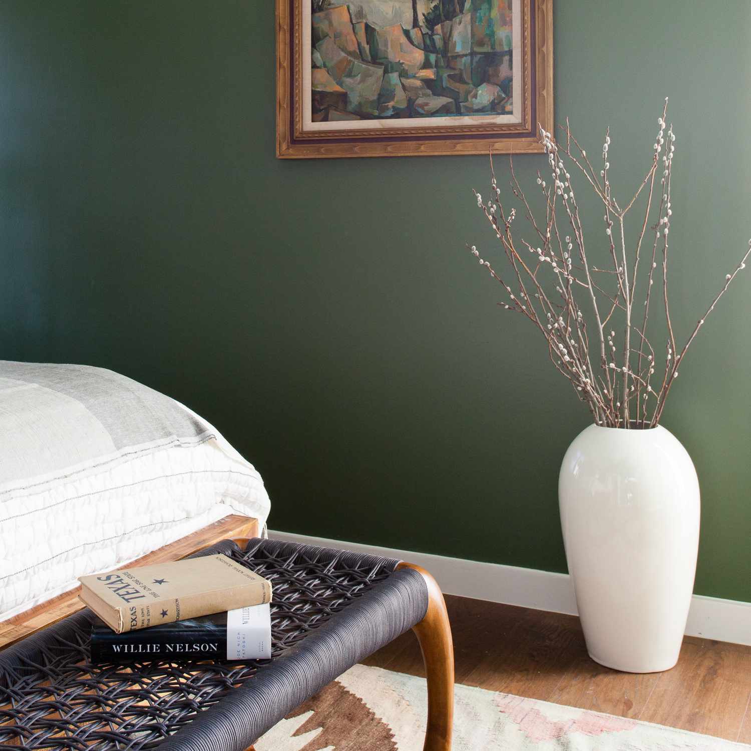 一间绿色的卧室，床脚放着一张编织的长凳