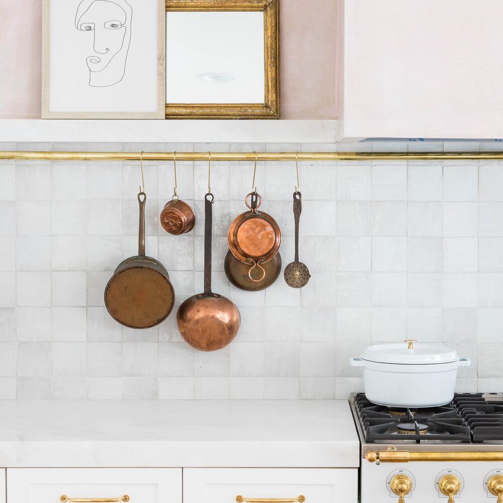 浅粉色的厨房，陈列着古色古香的铜炊具